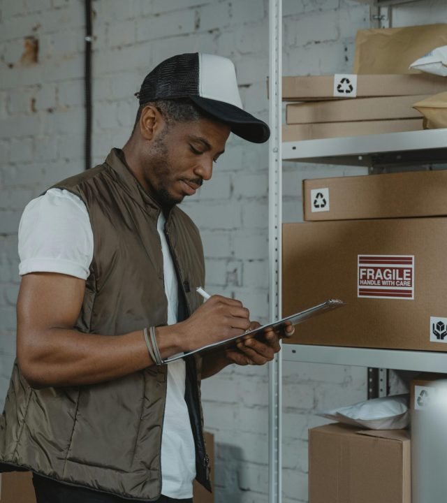 A young employee organizing shipping boxes in a warehouse.